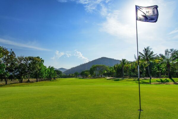 flag der flyver over golfbane på Majestic Creek Golf & Country Club i Hua Hin med bjerge i baggrunden