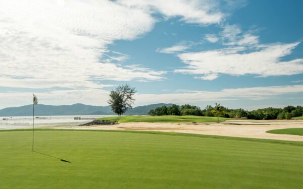 Phuket Golf Course ved Mission Hills med grønne fairways, hvide sandbunkere og havudsigt. En udfordrende golfbane beliggende ved stranden i