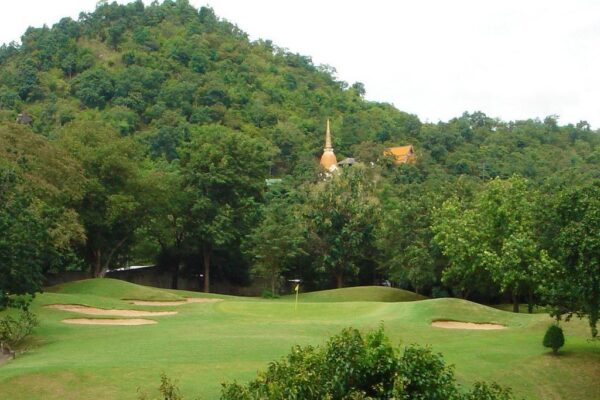 golfbane i Hua Hin, Thailand med træer og tempel i baggrunden