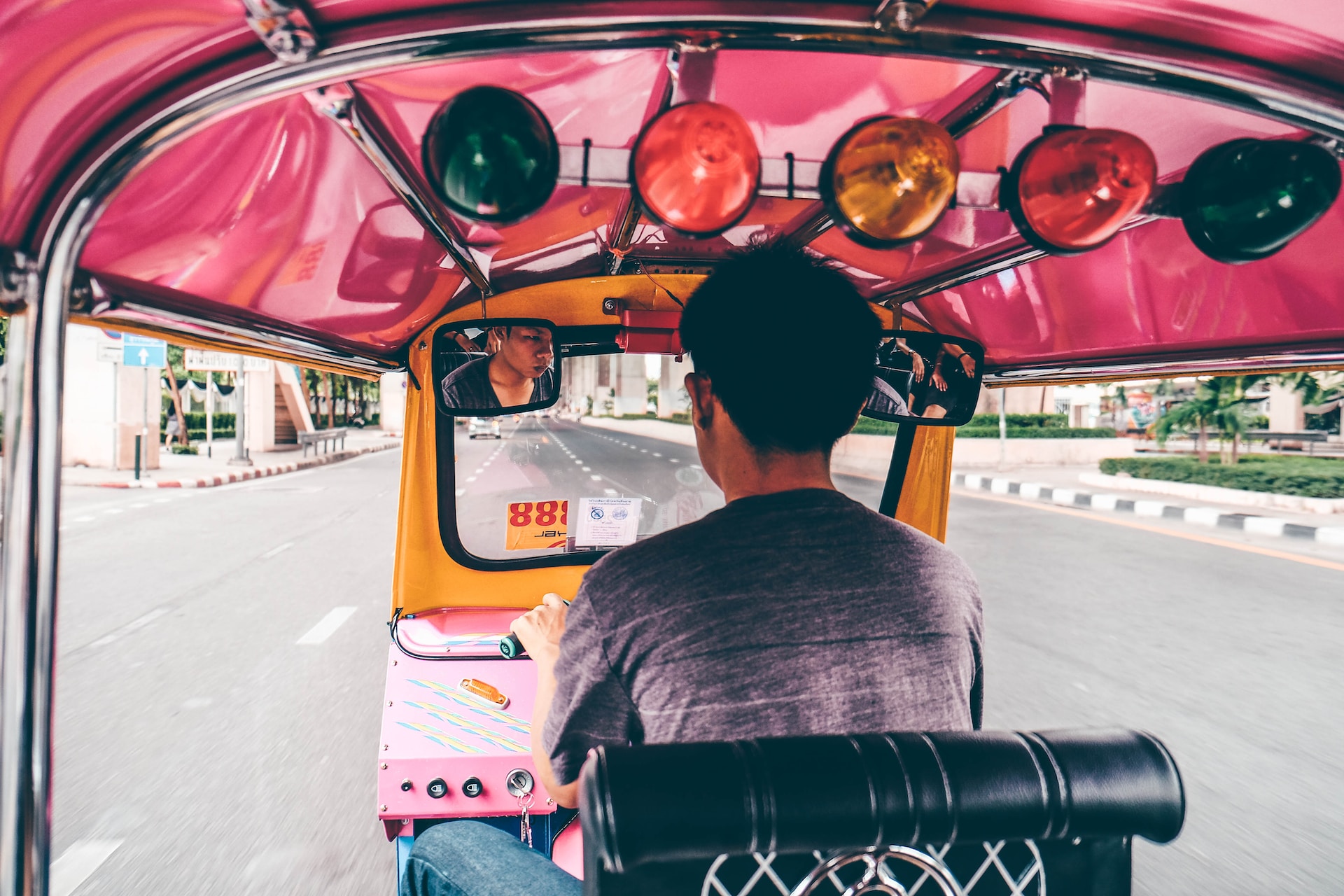 En mann kjører en rosa tuk-tuk i Bangkok, Thailand