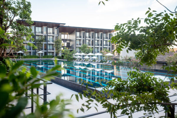 Moderne hotell i Krabi med stort basseng, grønne omgivelser og afslappende liggestole under hvite parasoller.